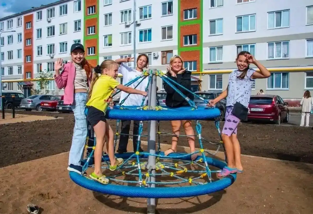 дети катаются на карусели во дворе дома