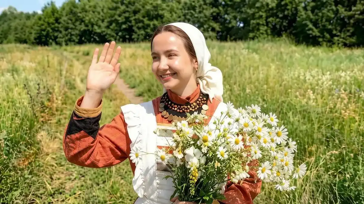 Женщина с букетом ромашек в руках на фоне природы
