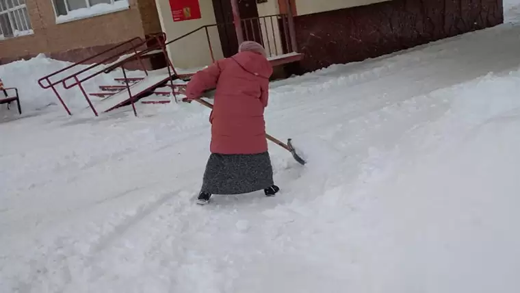 Горожанка убирает снег