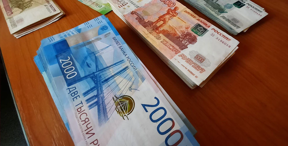 Денежные купюры, достоинством 2 000 и 5 000 рублей, разложенные на столе по стопкам