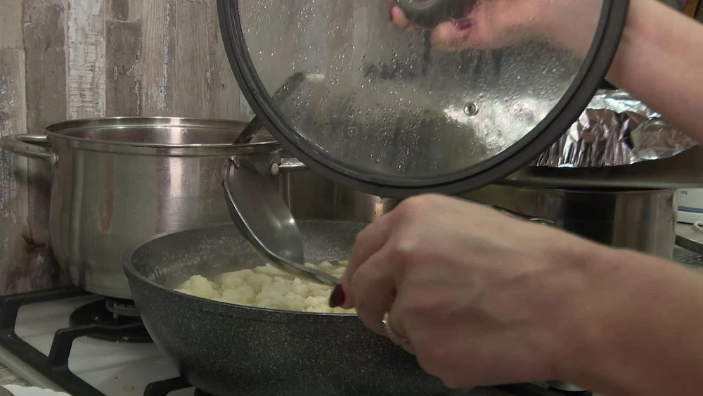 Женщина готовит еду в сковороде