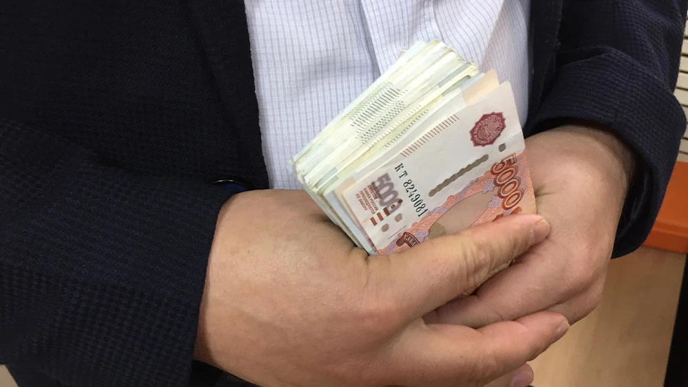 Денежные купюры номиналом 5 000 рублей в руках мужчины