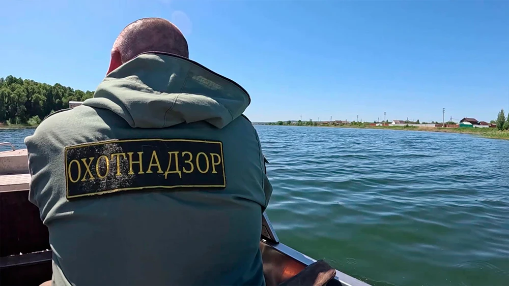 Сотрудник охотнадзора плывёт на лодке по озеру