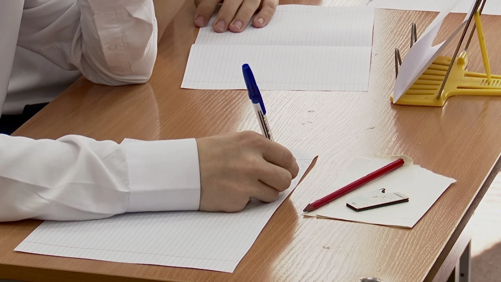ученик пишет в тетради на уроке в школе