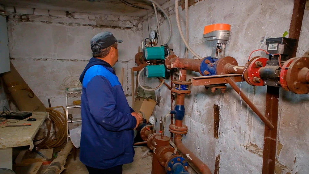 Рабочий проверяет систему отопления дома