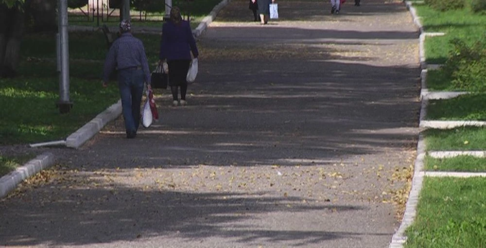 прохожие идут по тротуару