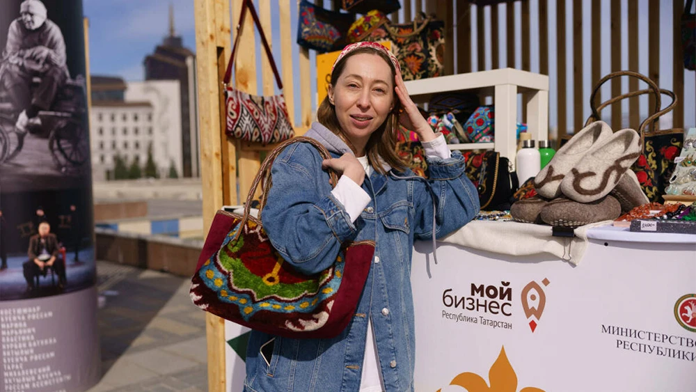 Женщина примеряет вещи на ярмарке