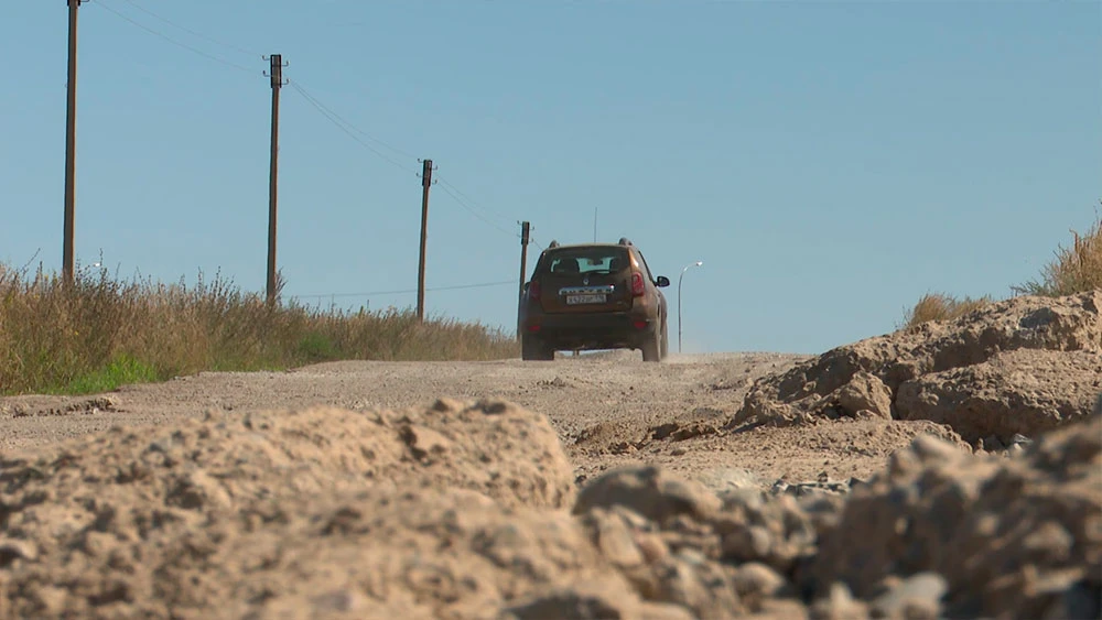 Автомобиль уезжает вдаль по разбитой дороге