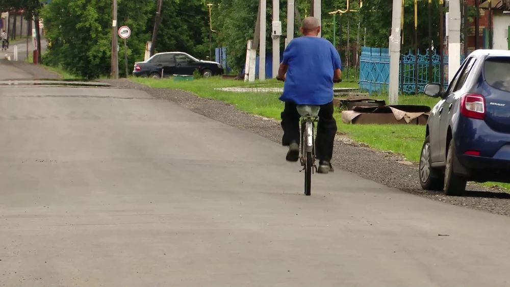мужчина едет на велосипеде по сельской дороге в татарстане