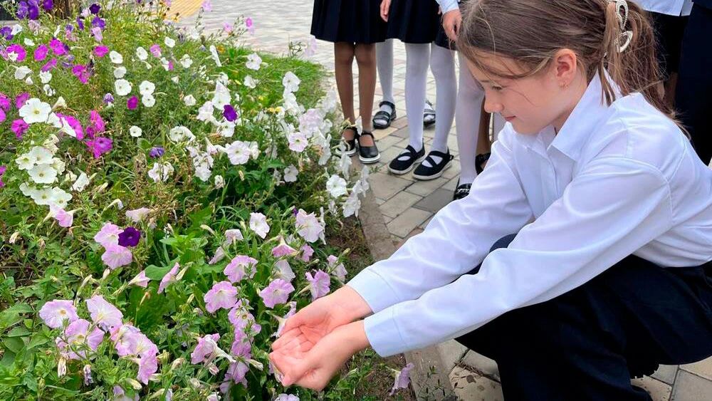 Девочка поливает цветы водой из ладоней