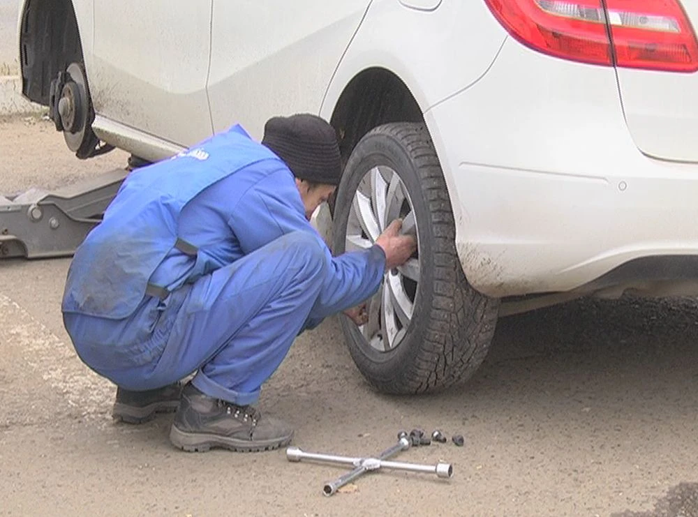 работник автосервиса меняет колесо