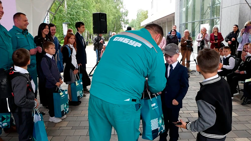 Сотрудник СИБУРа в Нижнекамске вручает мальчику школьные принадлежности