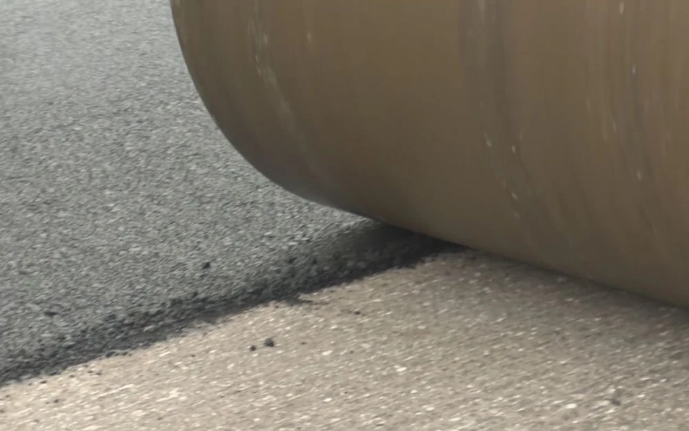 дорожный каток укладывает асфальт