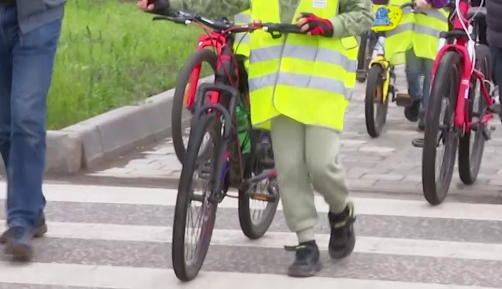 дети с велосипедами переходят дорогу по пешеходному переходу