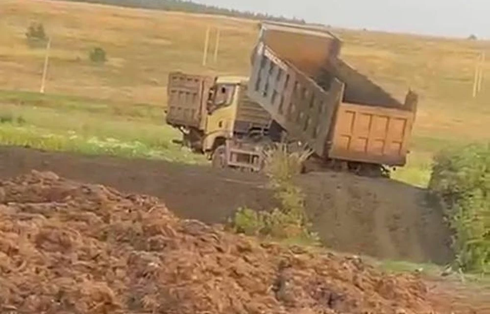 самосвал выгружает в поле