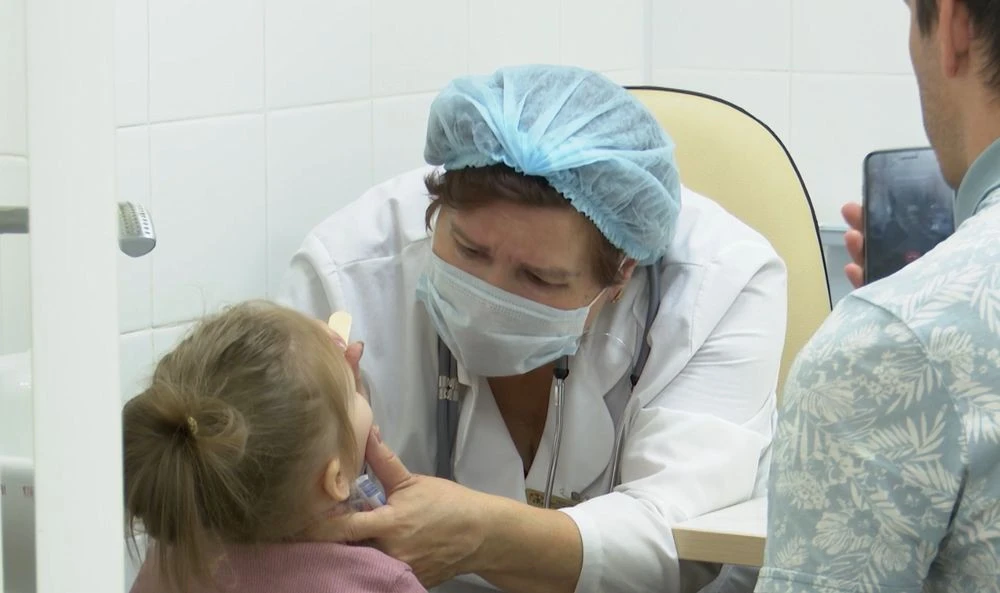 педиатр осматривает горло ребёнка