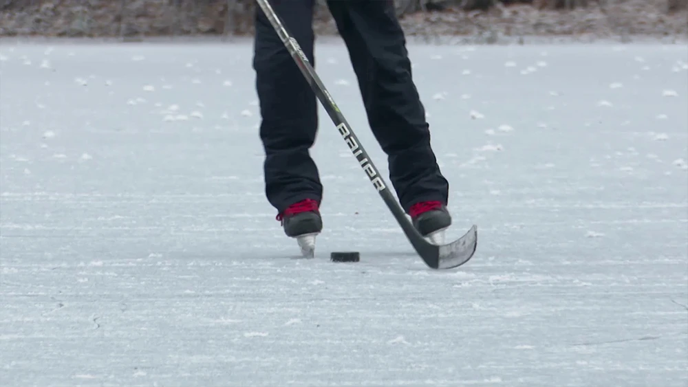 Спортсмен на коньках с клюшкой