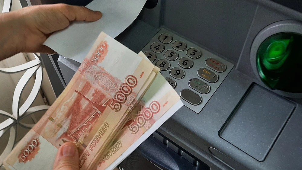 пятитысячные купюры банка России в руках человека у банкомата