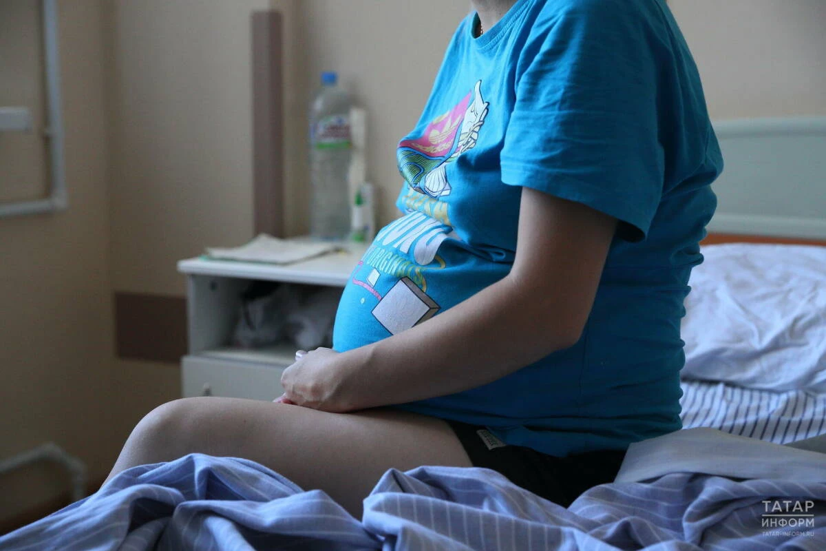 беременная женщина сидит на больничной койке
