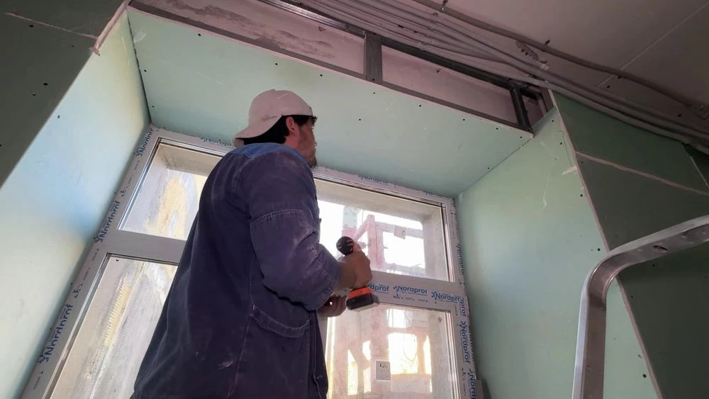 рабочий с шуруповёртом у окна