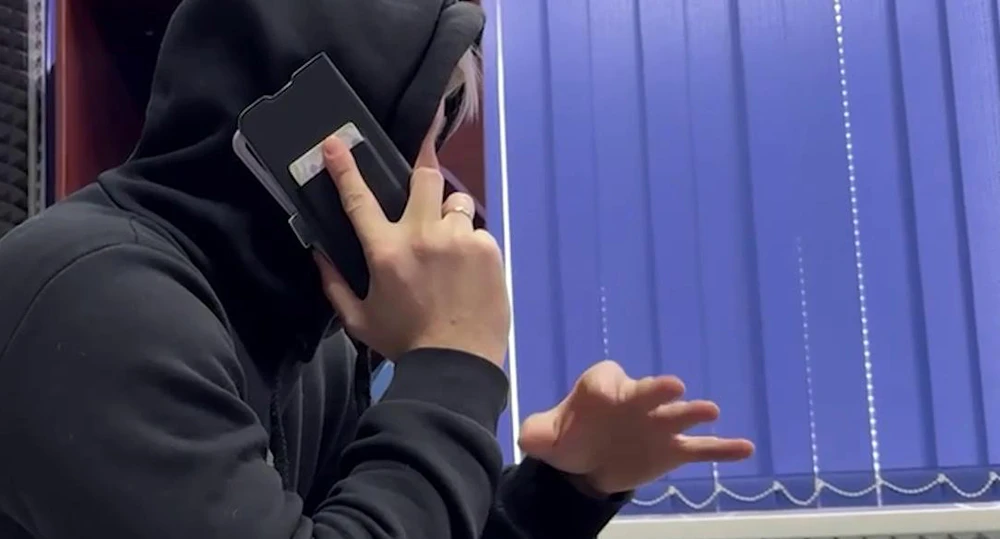 человек в капюшоне разговаривает по мобильному телефону