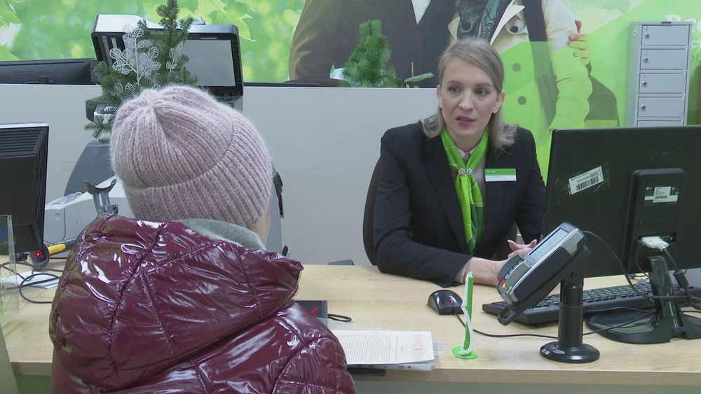 женщина клиент в отделении банка сидит напротив сотрудника банка