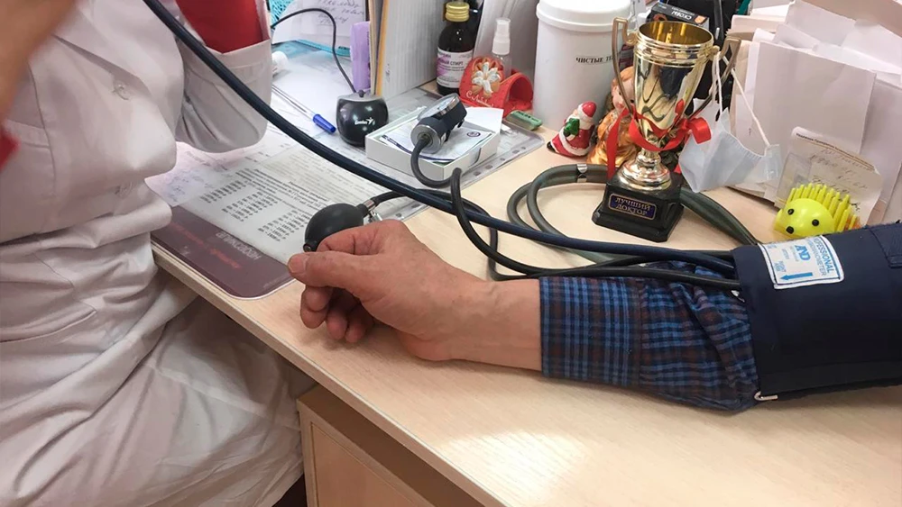 Врач измеряет давление пациенту тонометром