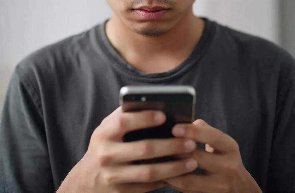 пользователь держит в руках смартфон и общается в мессенджере