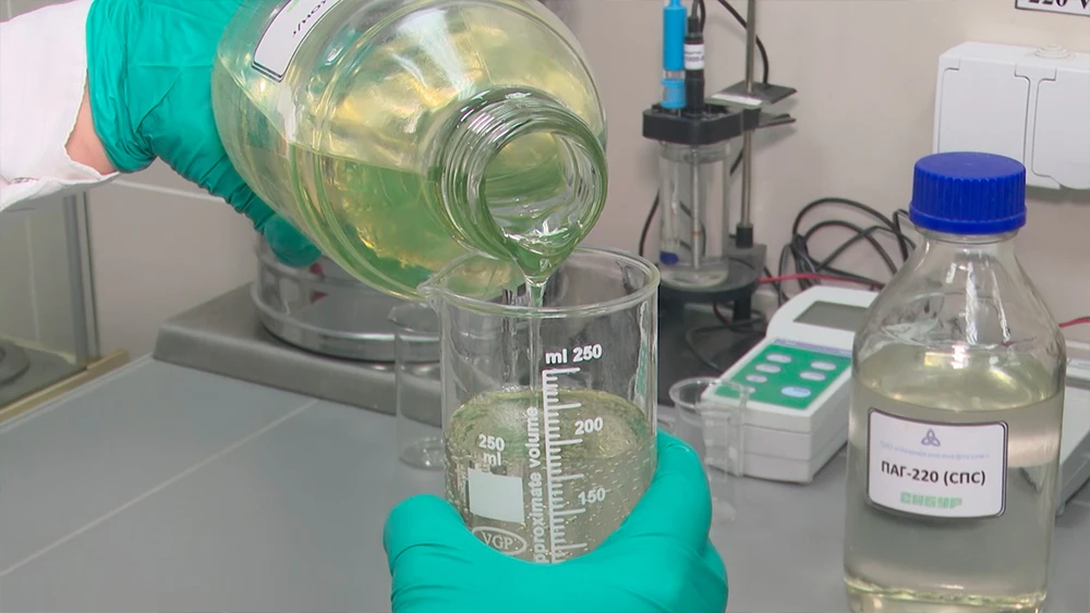 Переливает жидкость из бутылки в колбу