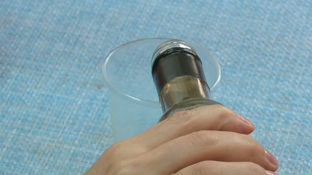 Наливает алкоголь в стаканчик