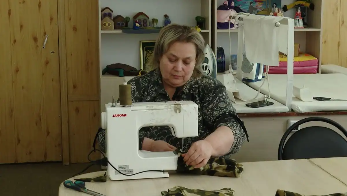 женщина шьёт шапку на швейной машинке