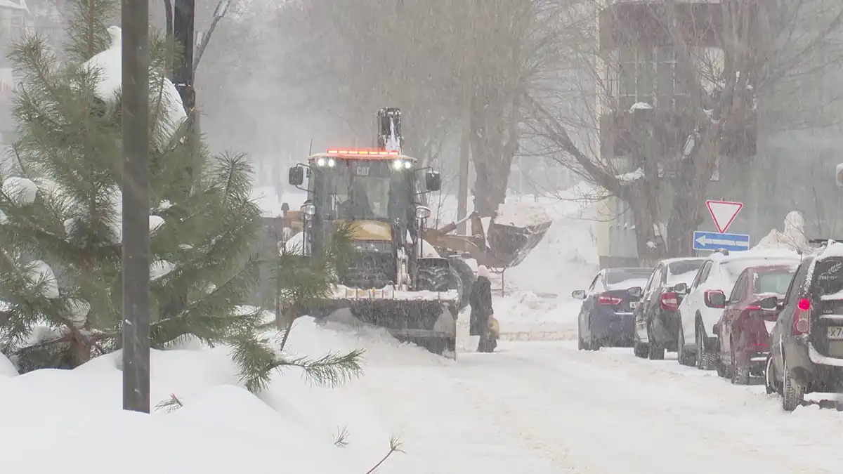 Метель, трактор чистит снег на дороге