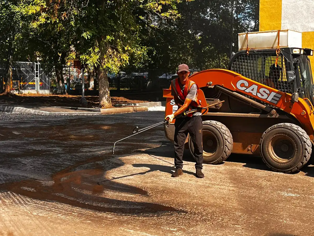 Дорожный рабочий ремонтирует асфальт во дворе