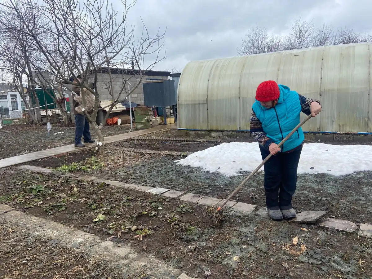 Мужчина и женщина убираются на дачном участке после зимы