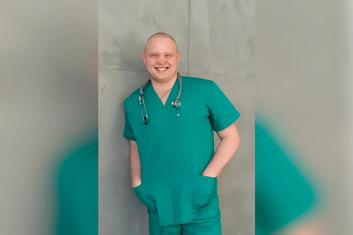 врач в медицинской форме улыбается в камеру