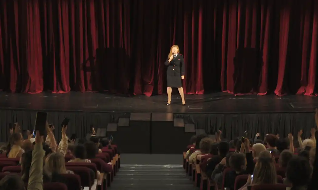 женщина в полицейской форме стоит на сцене перед толпой