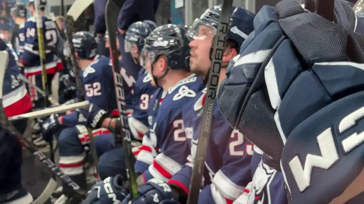 Хоккеисты нефтехимика сидят на скамейке и смотрят на куб