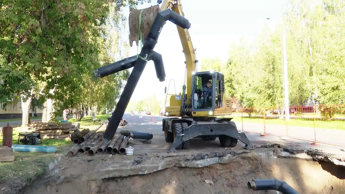 экскаватор ставит трубу