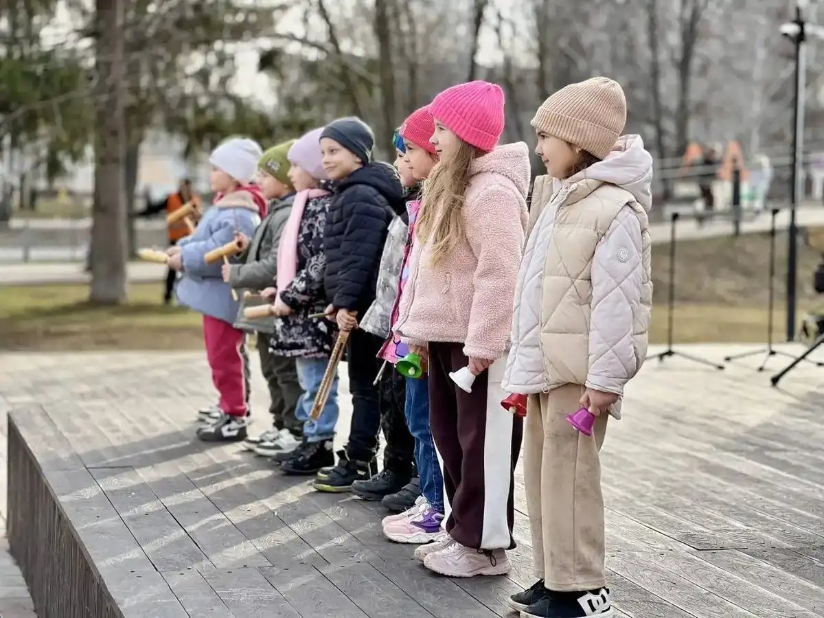 дети стоят на сцене с колокольчиками на улице