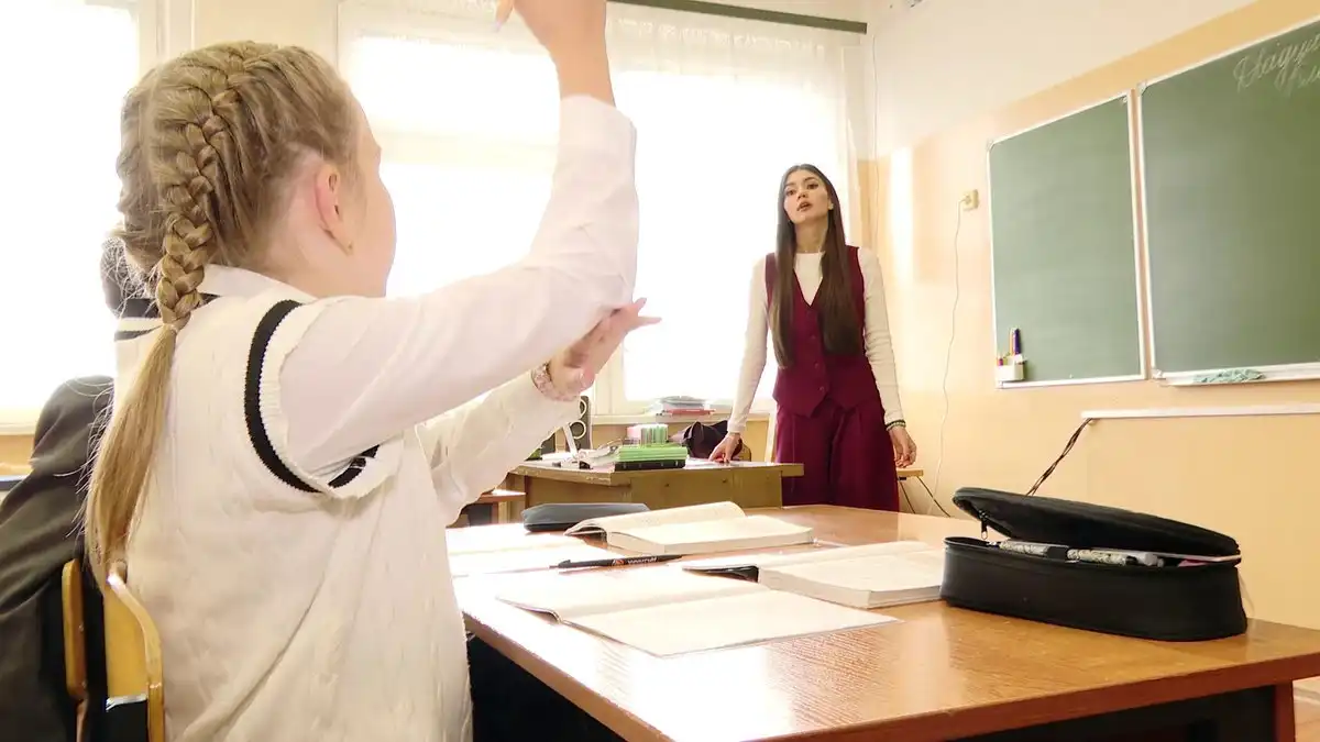 девочка школьница поднимает руку для ответа учителю