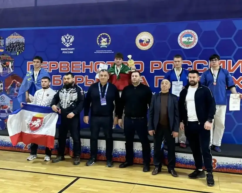 спортсмены с медалями на пьедестале рядом их тренеры