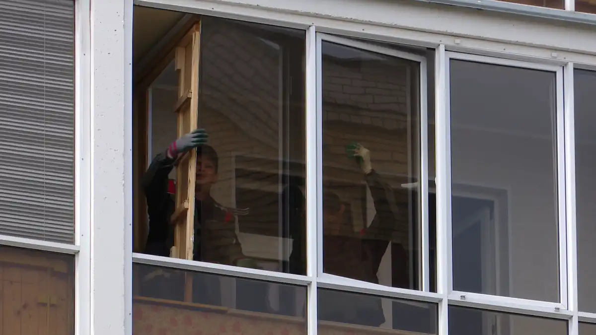 Слесари меняют окно на балконе разбитое взрывной волной после взрыва на Нижнекамскнефтехиме