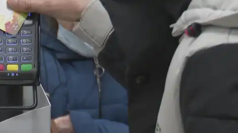 Покупательница расплачивается за товар в супермаркете картой через терминал для оплаты на кассе
