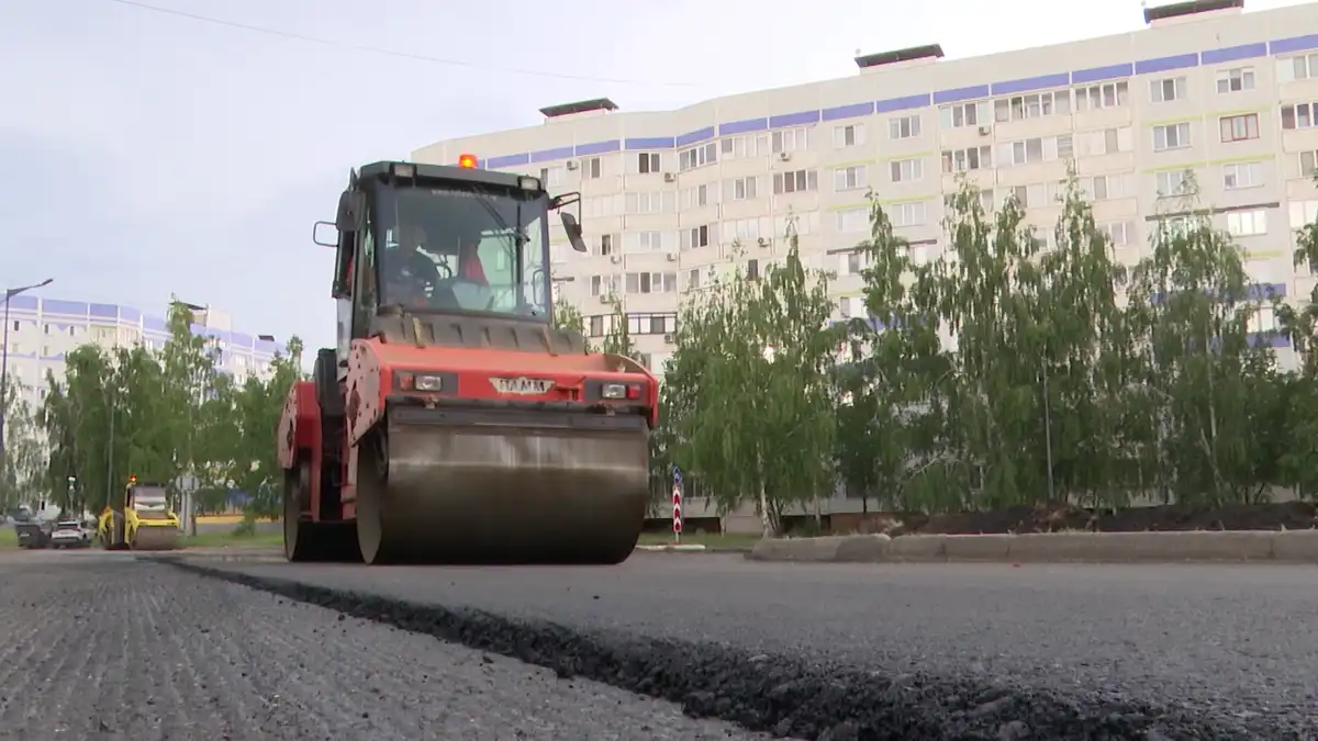 Дорожный каток укладывает асфальт на дороге