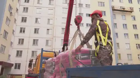 строитель цепляет груз к крану