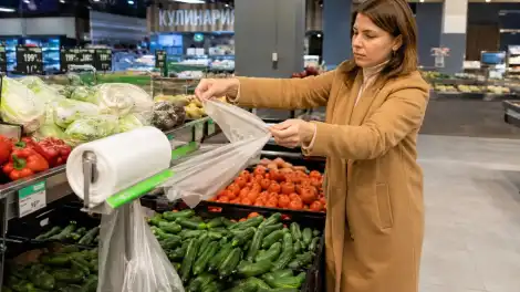 покупательница в магазине берёт полиэтиленовый пакет