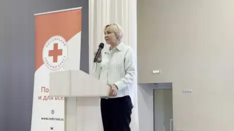 Александра Офицерова с микрофоном стоит за трибуной