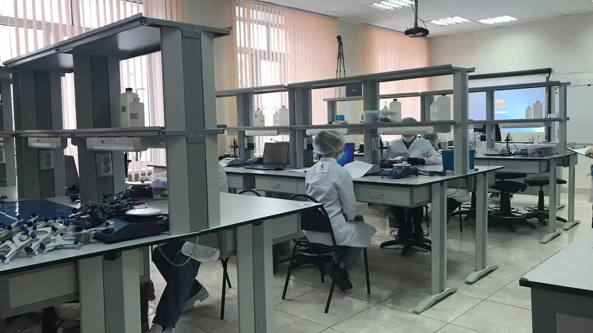 лаборанты в халатах сидят в лаборатории