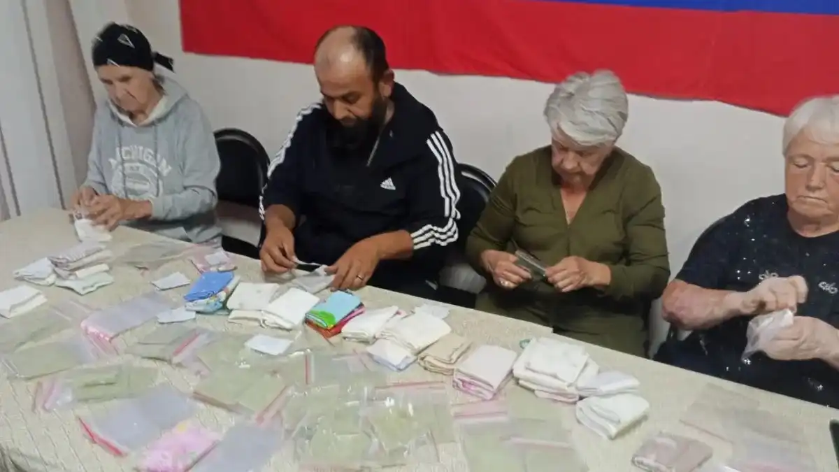 компания людей сидит за столом и упаковывает комплекты сухого душа