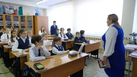 ученики сидят на партами и слушают учителя